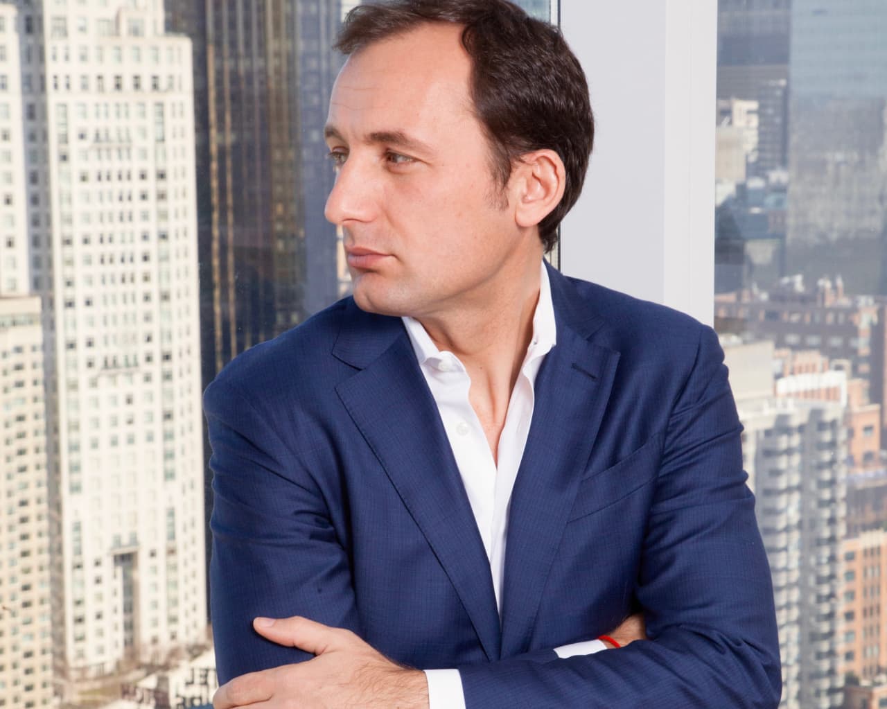 Arben Kane posing in front of a window overlooking several buildings